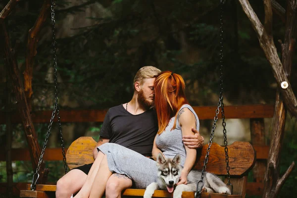 Beau couple avec chien sur une balançoire — Photo