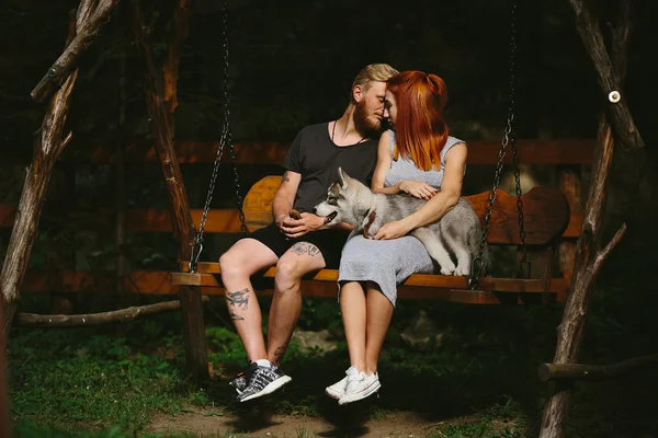 Mooi paar samen met hond op een schommel — Stockfoto