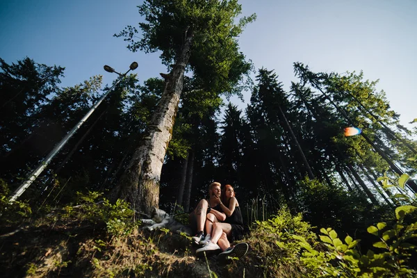 Belo casal sentado em uma floresta perto da árvore — Fotografia de Stock