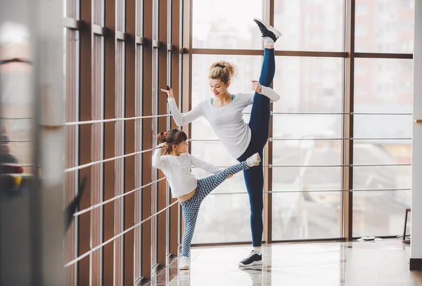 Mother learning daughter to make a high leg strech — Stock Photo, Image