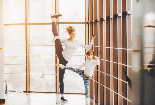 Madre aprendiendo hija para hacer un estiramiento de pierna alta — Foto de Stock