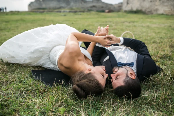 Pareja de boda acostada en la hierba — Foto de Stock