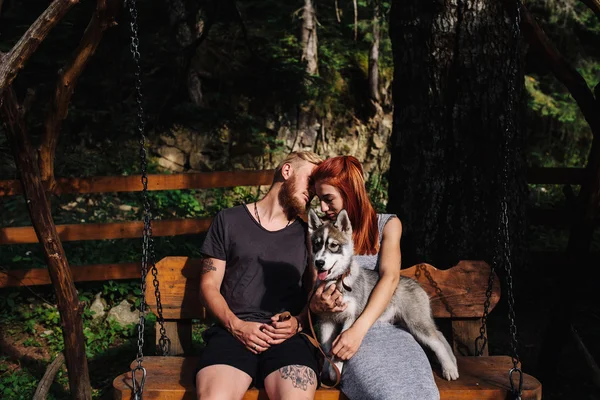 Schönes Paar mit Hund auf einer Schaukel — Stockfoto