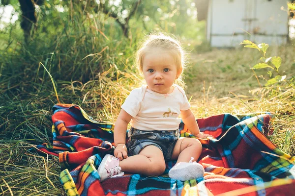 Mała dziewczynka siedzi na trawniku — Zdjęcie stockowe