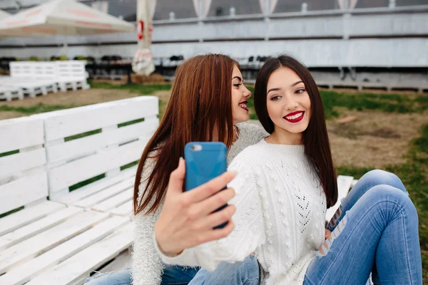 Dwie dziewczyny co selfie na ławce — Zdjęcie stockowe