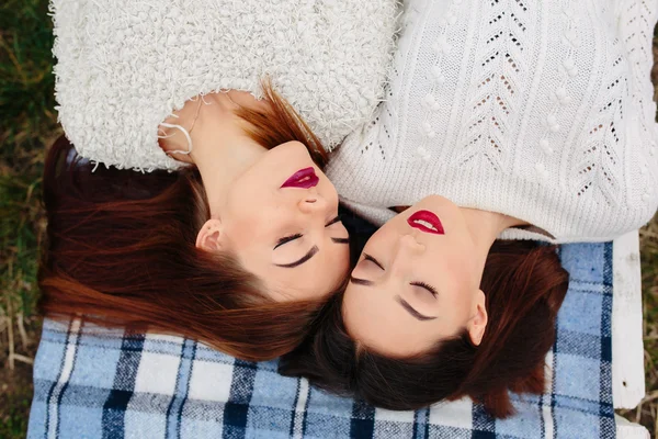 Dwie piękne dziewczyny leżą na ławce — Zdjęcie stockowe