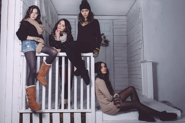 Four stylish models posing sitting on the fence — Stock Photo, Image