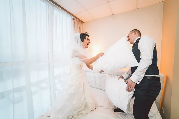 A menyasszony és a vőlegény egy szállodai szobában Párnacsata — Stock Fotó