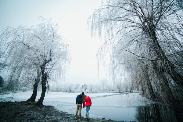 Vackra par poserar nära en fryst flod — Stockfoto