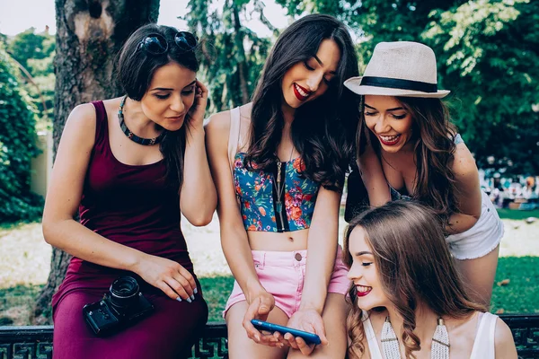 Fyra vackra unga flickor tittar på bilderna — Stockfoto