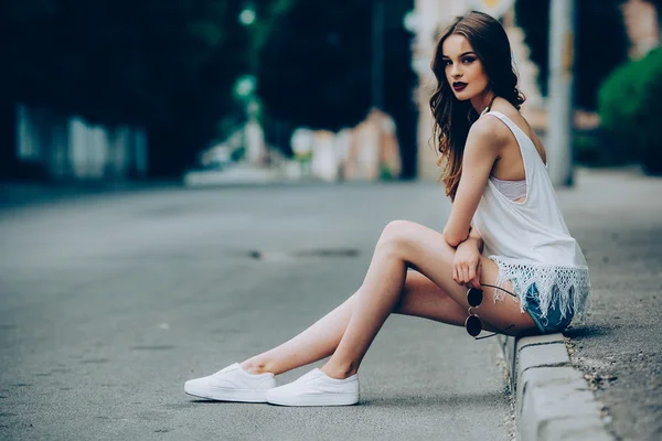 Menina bonita sentada em uma rua da cidade — Fotografia de Stock