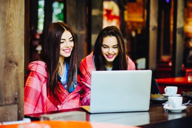 İki kız dizüstü bilgisayarda bir şey izliyor.