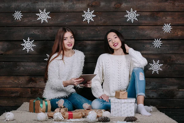 Due belle ragazze con una tavoletta, tra regali — Foto Stock