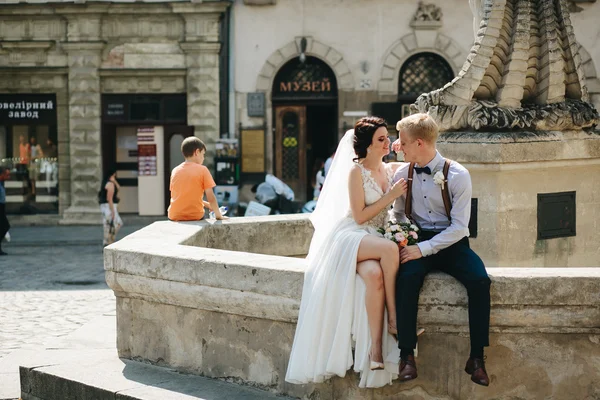 Bruden och brudgummen poserar vid fontänen — Stockfoto