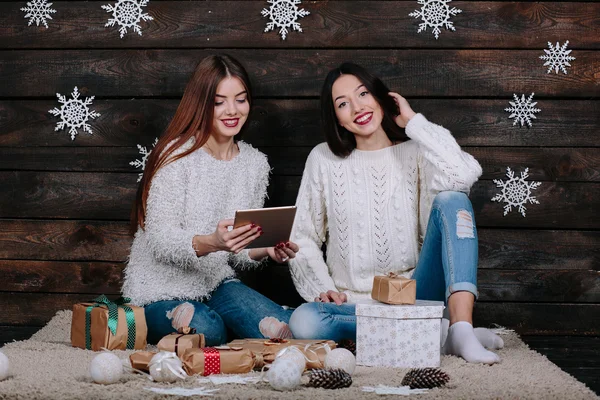 Två vackra flickor med en tablett, mellan gåvor — Stockfoto
