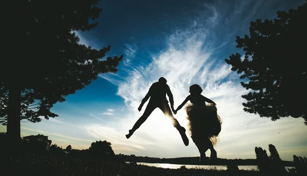 Groom and bride jumping against the beautiful sky — Stock Photo, Image