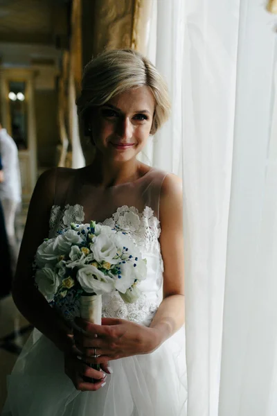 Belle mariée dans une robe de mariée, par fenêtre . — Photo