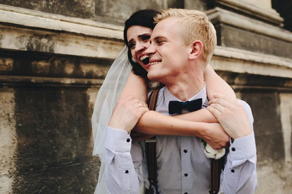 Groom carries bride on his back — Stock Photo, Image