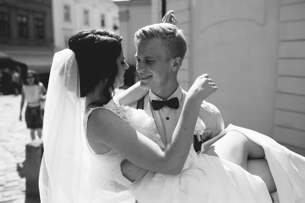 Groom carries bride in his arms — Stock Photo, Image