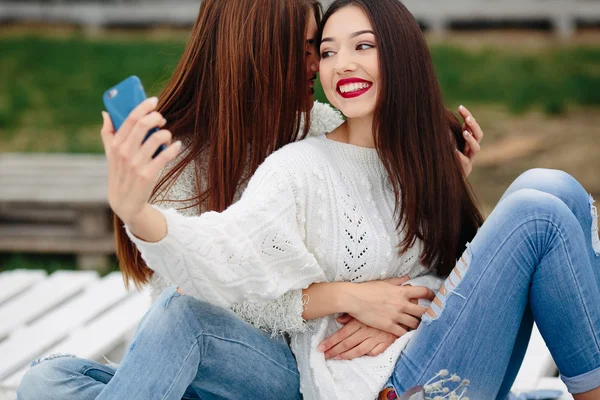 Dwie dziewczyny co selfie na ławce — Zdjęcie stockowe