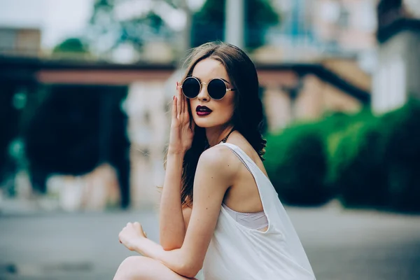 Belle fille dans des lunettes de soleil assis — Photo