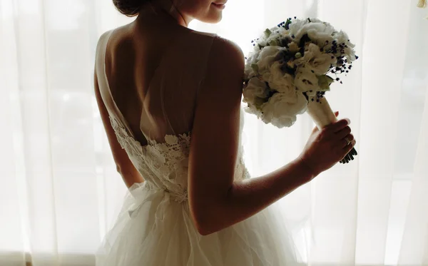 Hermosa novia en un vestido de novia, por ventana . — Foto de Stock