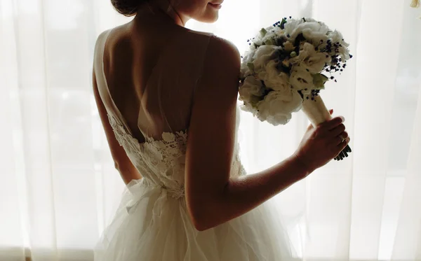 Beautiful bride in a wedding dress, by window. — Stock Photo, Image