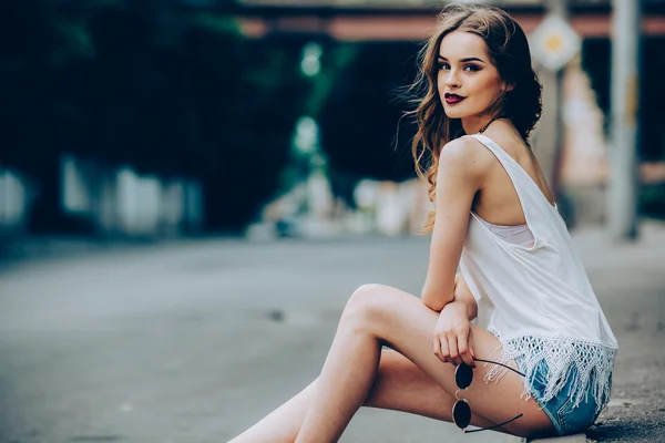 Menina bonita sentada em uma rua da cidade — Fotografia de Stock