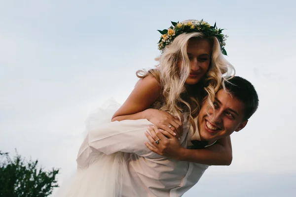 Bräutigam trägt Braut auf dem Rücken ins Freie — Stockfoto