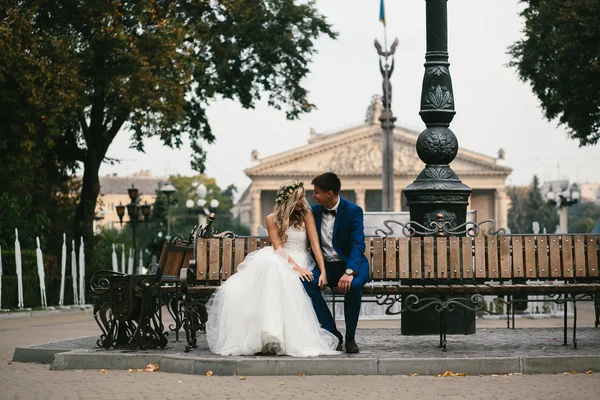 Pareja de boda relajándose en un banco — Foto de Stock