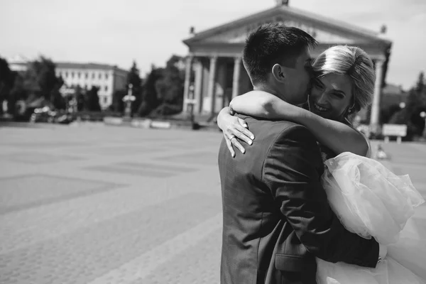 Novio sostiene novia en sus brazos y retorcido — Foto de Stock