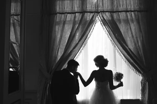 Невеста и жених стоят перед окном — стоковое фото