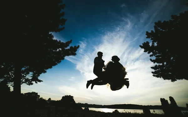 Novio y novia saltando contra el hermoso cielo — Foto de Stock