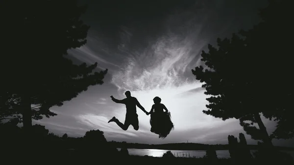 Sposo e sposa saltando contro il bel cielo — Foto Stock