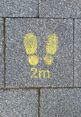 İngiltere, Weston-super-Mare 'de bir kaldırıma şablonla yazılmış bir tabela, iki metre uzakta durmaları için kuyrukta bekleyenleri uyarıyor.