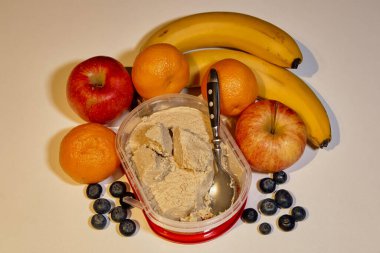 Taze meyve karışımı kremalı helva kabını sarar ve kaşıkla servis edilmeye hazırdır..