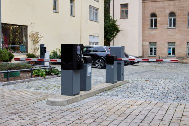 Otomatik park engeli, konut otoparkının girişinde kontrol terminali ve yükseltilmiş kapı. Park etmiş arabaları ve apartmanları olan şehir avlusu. Erişim denetimi ve park yönetimi kavramı.