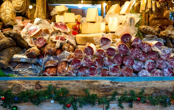 Geleneksel bir pazarda sergilenen bol miktarda pişmiş et, salam, prosciutto ve zanaatkar peyniri. Şenlikli dekoratif ahşap tezgah, gurme gıda konsepti, yerel lezzetler ve Avrupa mutfak geleneği..