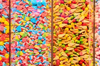 Şekerci dükkanındaki şeffaf kaplarda renkli şekerleme çeşitleri. Değişik şekil ve renklerde parlak jöleli şekerler. Şekerci dükkanı kavramı, şeker arkaplanı, çocukluk, parti ikramı ve şekerleme.