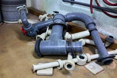 Endüstriyel plastik PVC borular, tesisat ve vanalar teknik bir odanın zeminine yerleştirilmiş. Su tedariği, drenaj veya endüstriyel sıvı yönetimi için kullanılan tesisat sistemi bileşenleri.
