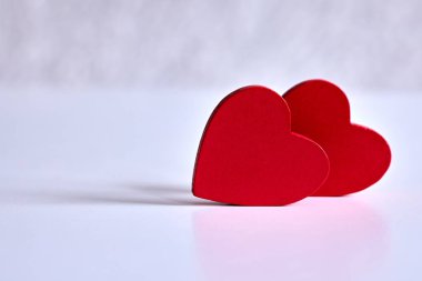 İki kırmızı kalp, beyaz bir yüzeyde yumuşak ışık ve kopyalama alanı ile şekillenir. Aşkı, ortaklığı ve Sevgililer Günü 'nü simgeleyen asgari romantik hayat.