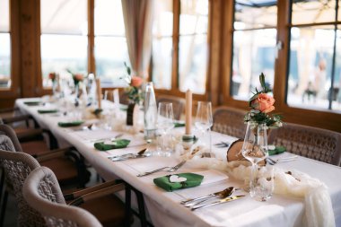 Çiçekli süsler, mumlar, cam eşyalar ve davetliler için hazırlanmış, şık dekore edilmiş düğün masası..