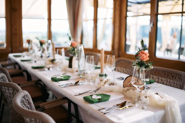 Çiçekli süsler, mumlar, cam eşyalar ve davetliler için hazırlanmış, şık dekore edilmiş düğün masası..