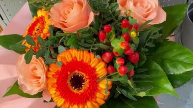 Şeftali gülleri, turuncu gerbera, yeşil yapraklar ve kırmızı dekoratif böğürtlenli karışık çiçek buketi yakın plan. Hediyeler, kutlamalar ya da çiçekçiler için uygun taze çiçek aranjmanı..