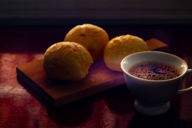 Pao de queijo e cafe sobre mesa.
