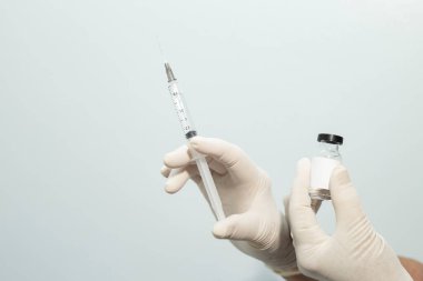 Ellerinde aşı ve şırınga tutan eldivenli hemşire elleri..