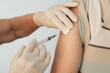  Hemşirenin ellerine yakın çekim, eldivenlerle, yaşlı hastanın koluna aşı uygulamak..