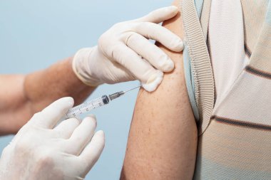  Hemşirenin ellerine yakın çekim, eldivenlerle, yaşlı hastanın koluna aşı uygulamak..