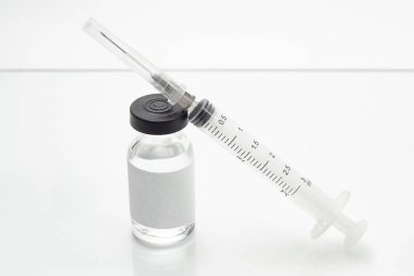 Aşı şişesi ve beyaz masa yüzeyinde bir şırınga..