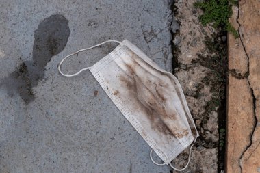 Beyaz Covid-19 koruyucu maske. Uygunsuz bir şekilde sokağa atılmış..